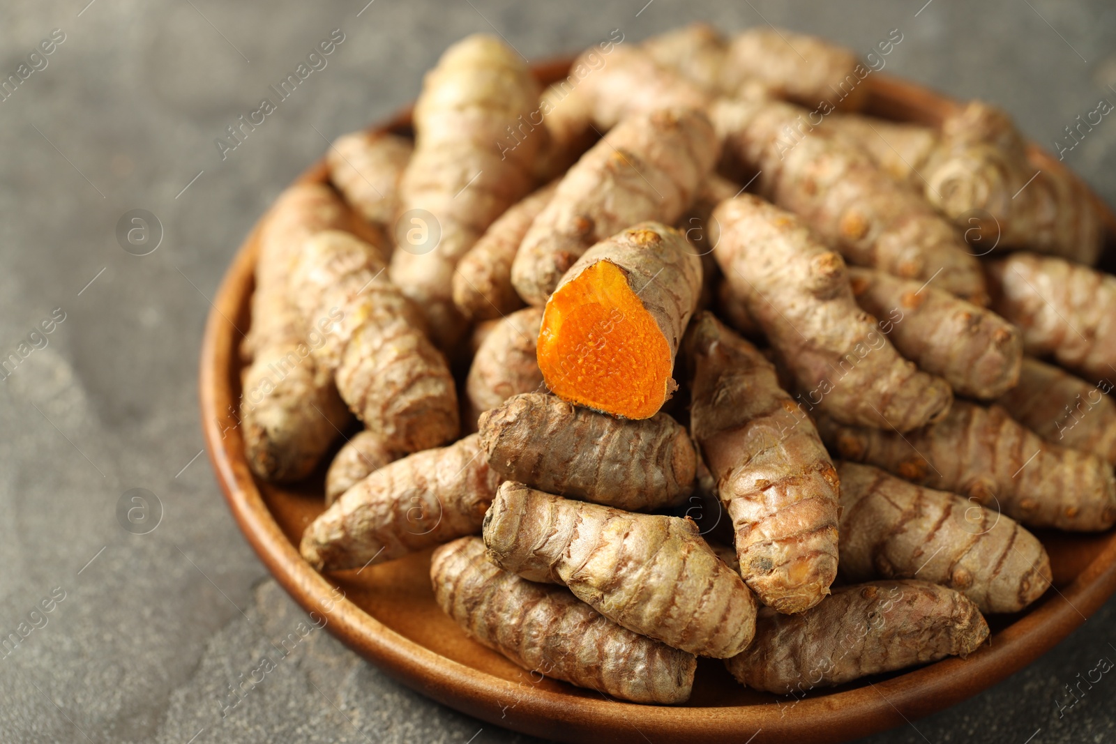 Photo of Raw tumeric rhizomes on grey table, closeup