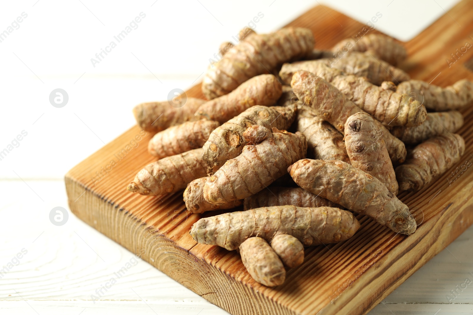 Photo of Raw tumeric rhizomes on white table, closeup