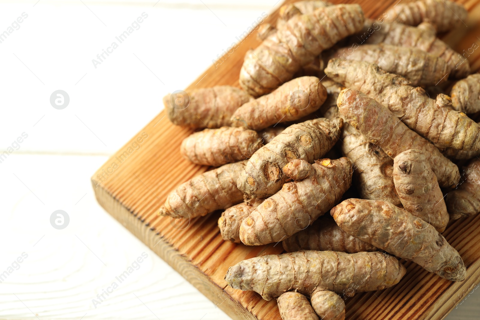 Photo of Raw tumeric rhizomes on white table, closeup