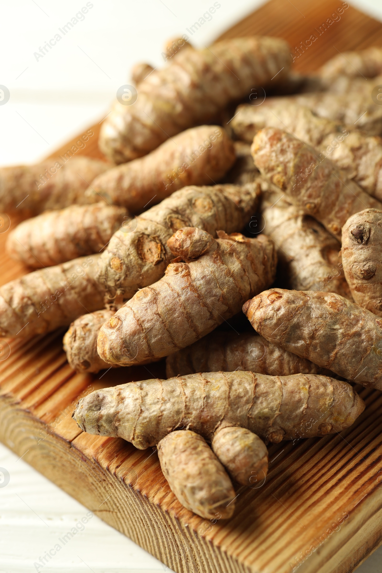 Photo of Raw tumeric rhizomes on white table, closeup