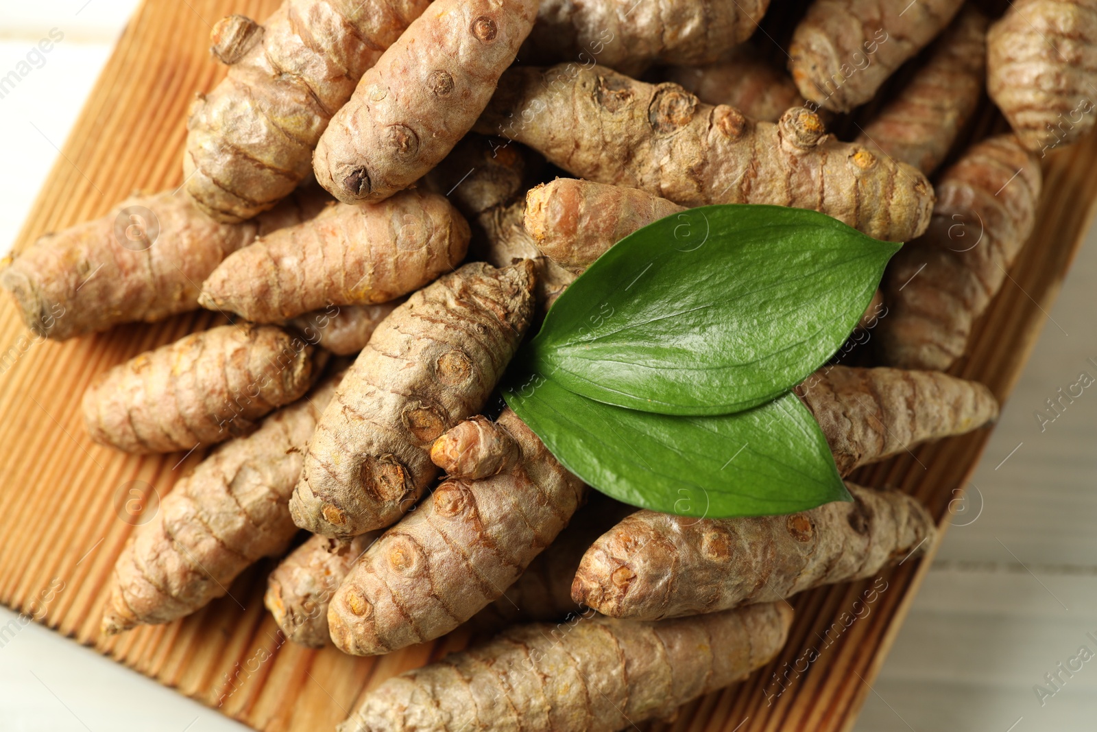 Photo of Raw tumeric rhizomes on white table, closeup