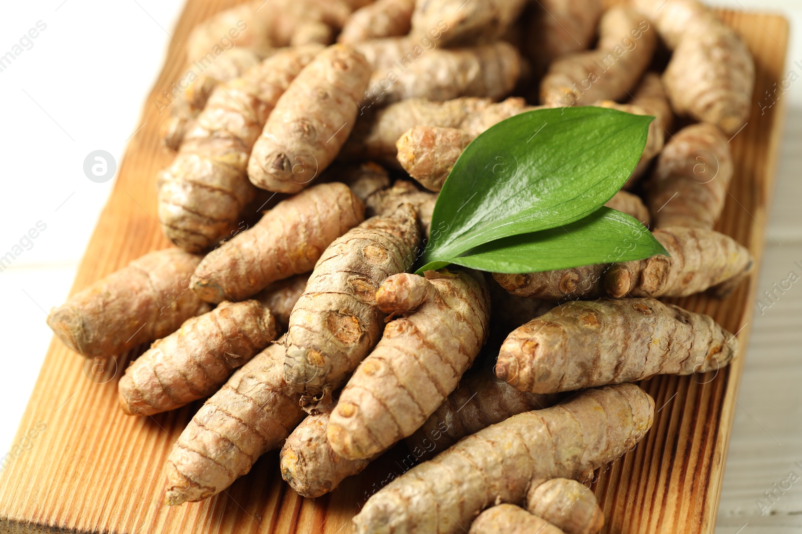 Photo of Raw tumeric rhizomes on white table, closeup