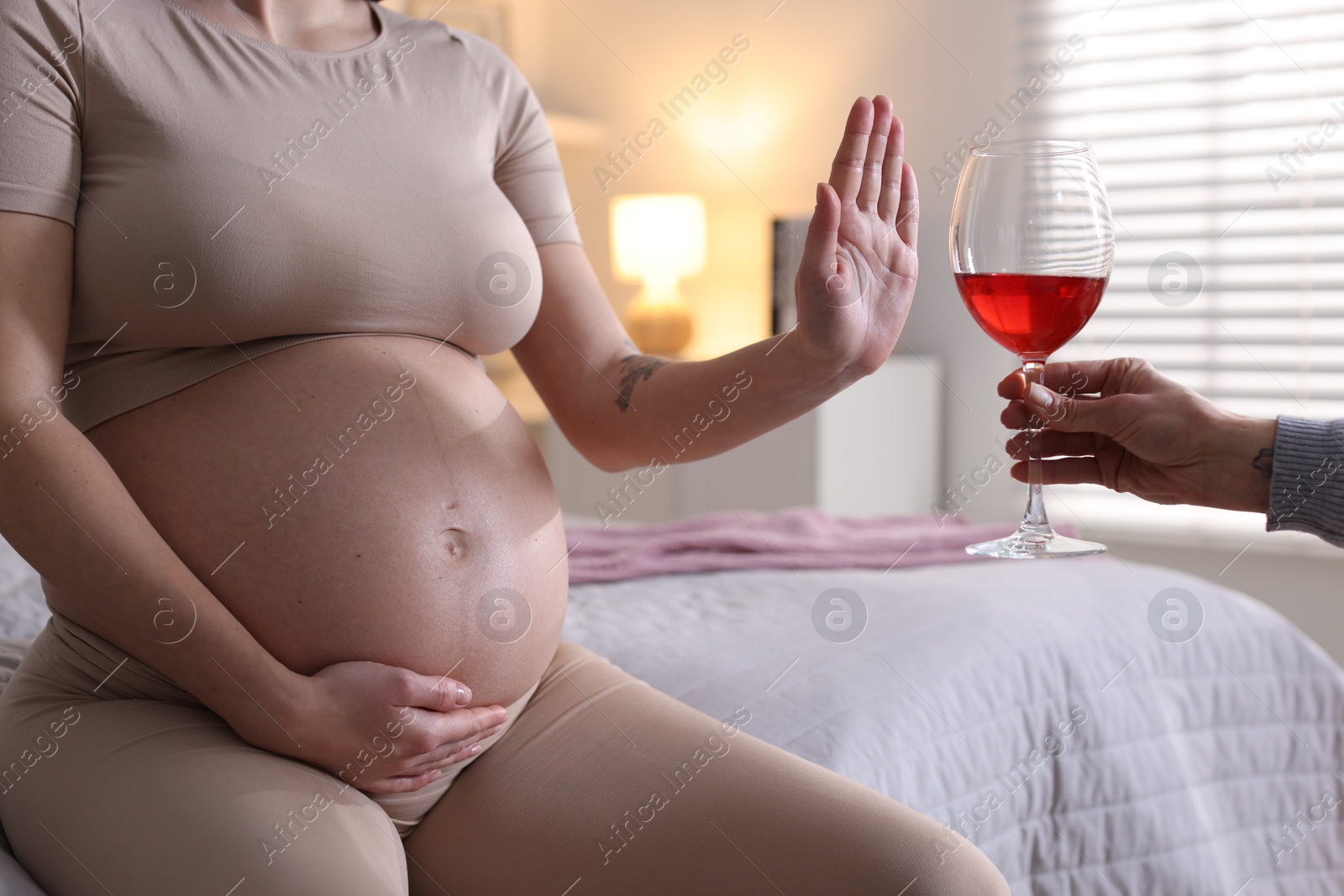 Photo of Pregnant woman refusing glass of red wine at home, closeup