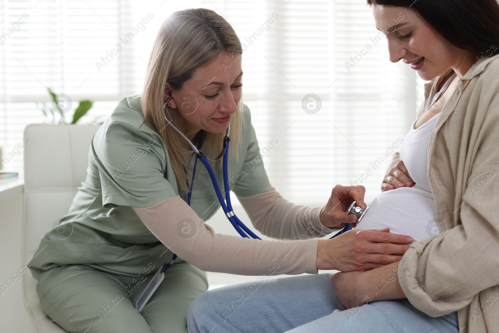 Photo of Pregnancy checkup. Doctor with stethoscope listening baby's heartbeat in patient's tummy indoors