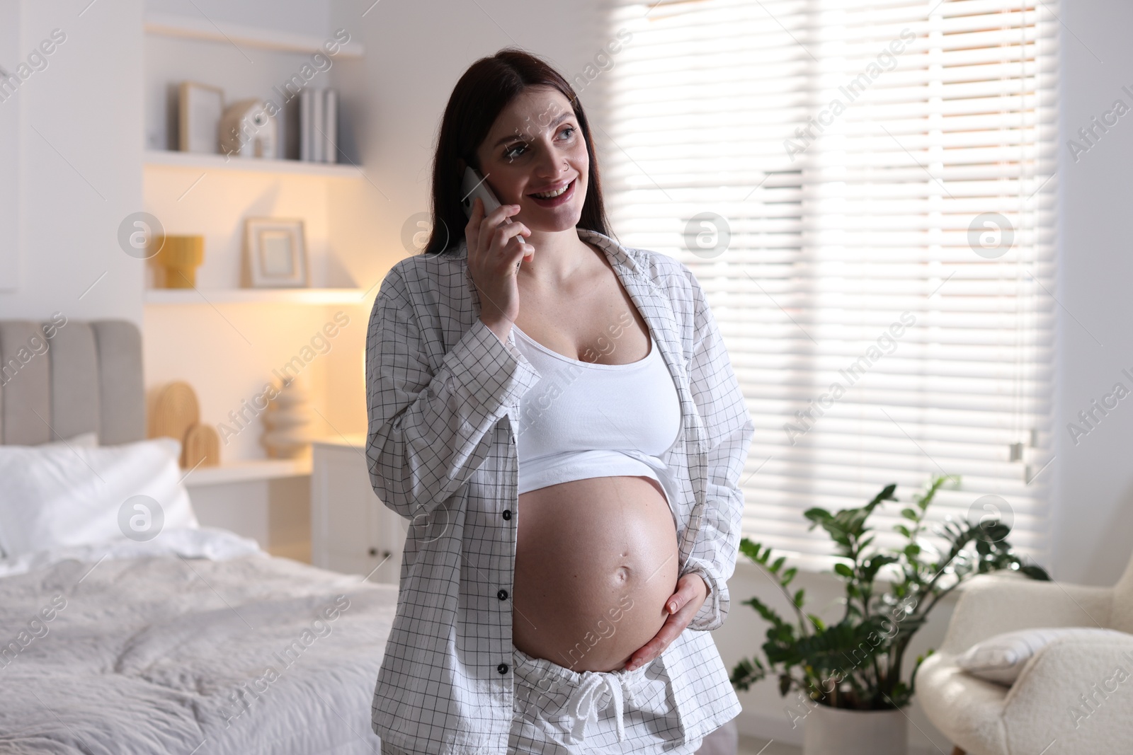 Photo of Beautiful pregnant woman talking on phone at home