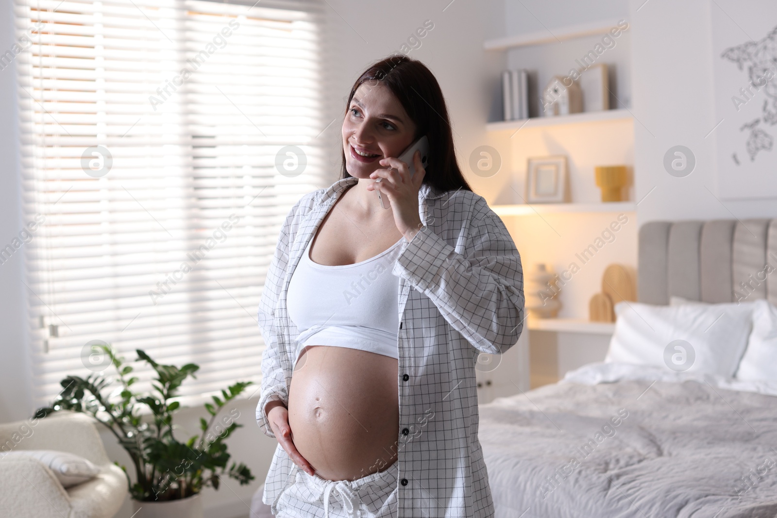 Photo of Beautiful pregnant woman talking on phone at home