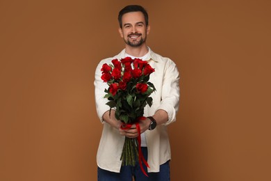 Photo of Happy Valentine's Day. Handsome man with bouquet of roses on brown background