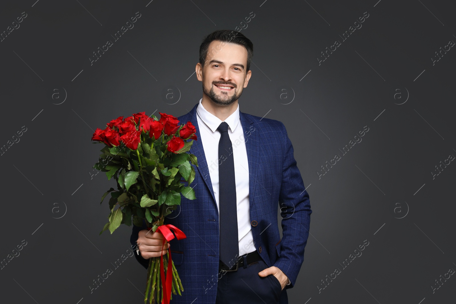 Photo of Happy Valentine's Day. Handsome man with bouquet of roses on grey background