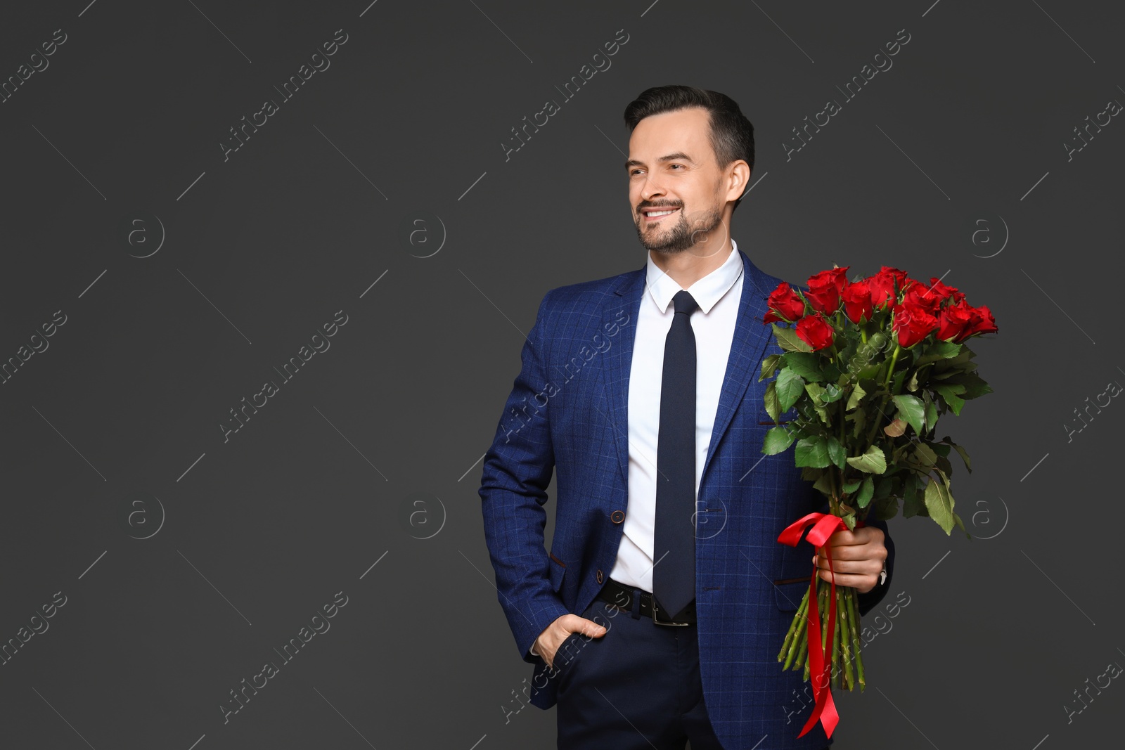 Photo of Happy Valentine's Day. Handsome man with bouquet of roses on grey background. Space for text