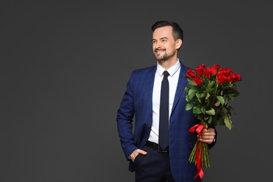 Photo of Happy Valentine's Day. Handsome man with bouquet of roses on grey background. Space for text