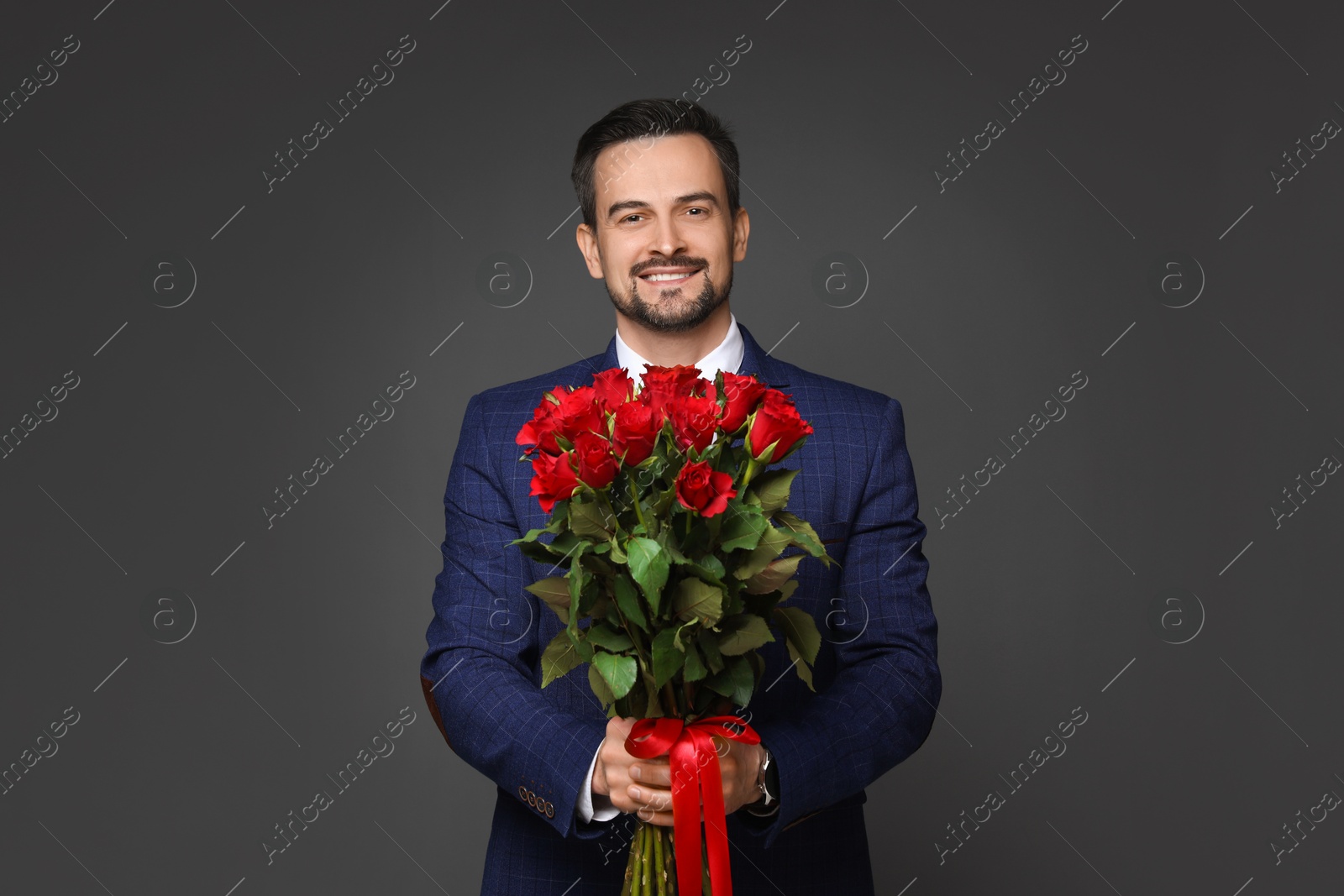 Photo of Happy Valentine's Day. Handsome man with bouquet of roses on grey background