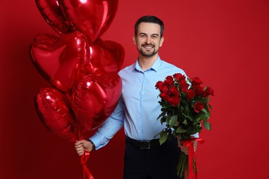 Photo of Happy Valentine's Day. Handsome man with bouquet of roses and heart shaped balloons on red background