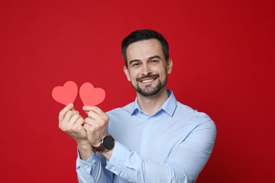 Photo of Happy Valentine's Day. Handsome man with paper hearts on red background