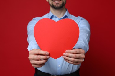 Photo of Happy Valentine's Day. Man with paper heart on red background, closeup