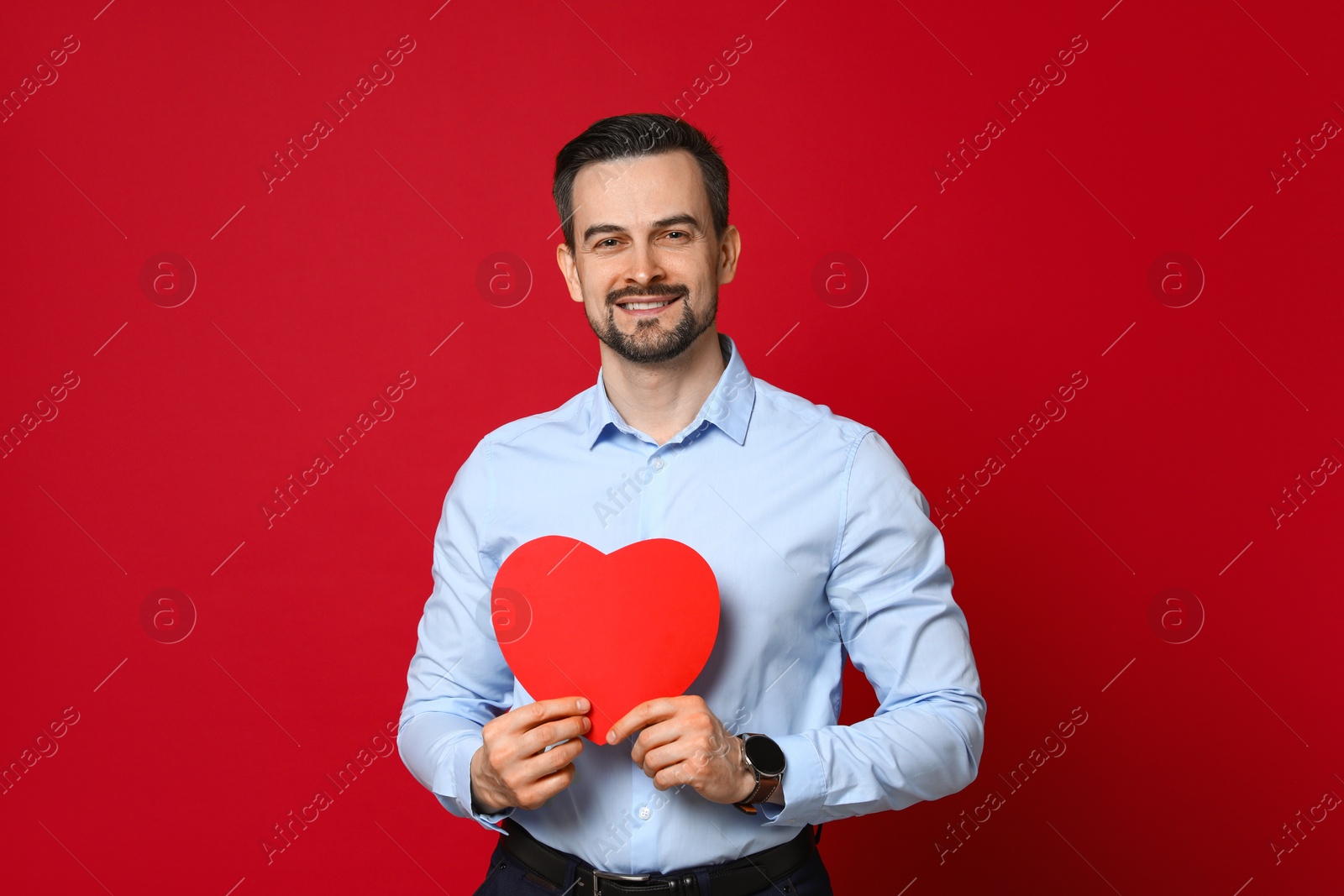 Photo of Happy Valentine's Day. Handsome man with paper heart on red background