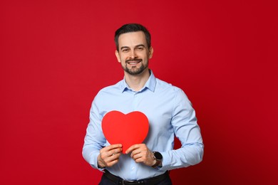 Photo of Happy Valentine's Day. Handsome man with paper heart on red background