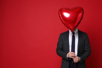 Photo of Happy Valentine's Day. Handsome man with heart shaped balloon on red background. Space for text