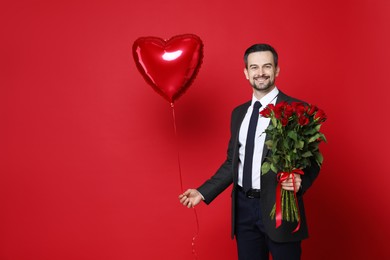 Photo of Happy Valentine's Day. Handsome man with heart shaped balloon and bouquet of roses on red background. Space for text