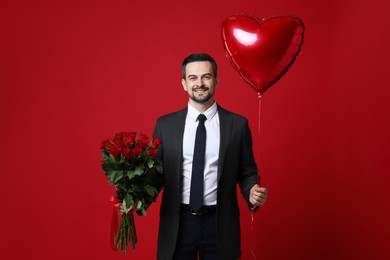 Photo of Happy Valentine's Day. Handsome man with heart shaped balloon and bouquet of roses on red background