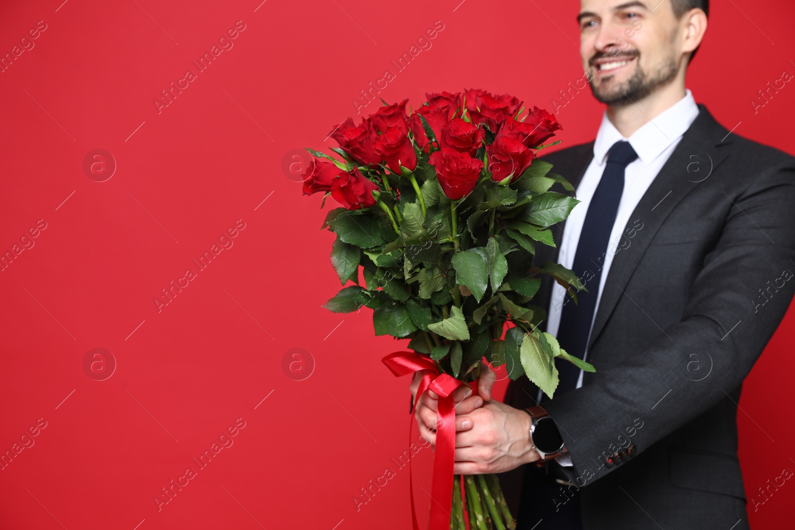 Photo of Happy Valentine's Day. Man with bouquet of roses on red background, closeup. Space for text