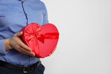 Photo of Happy Valentine's Day. Man with heart shaped gift box on white background, closeup. Space for text