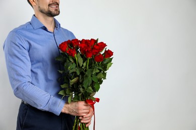 Photo of Happy Valentine's Day. Man with bouquet of roses on white background, closeup. Space for text