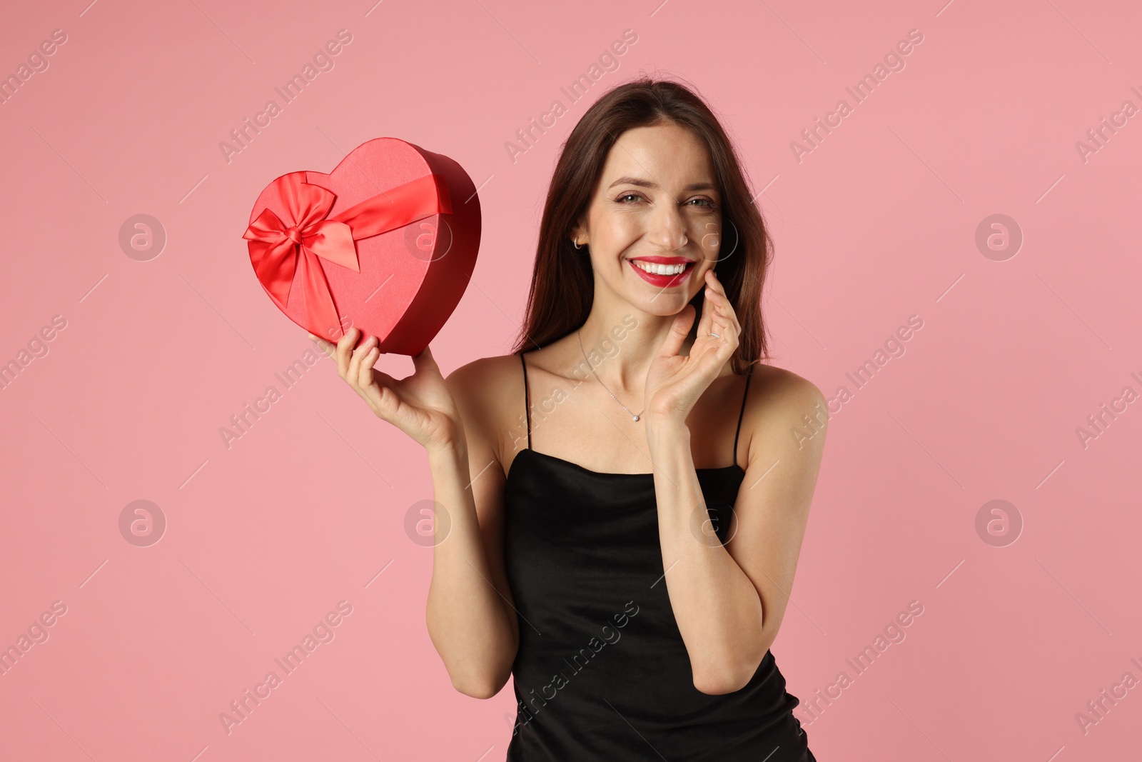 Photo of Happy Valentine's Day. Beautiful woman with heart shaped gift box on pink background