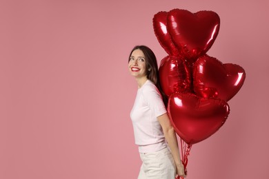 Photo of Happy Valentine's Day. Beautiful woman with heart shaped balloons on pink background. Space for text