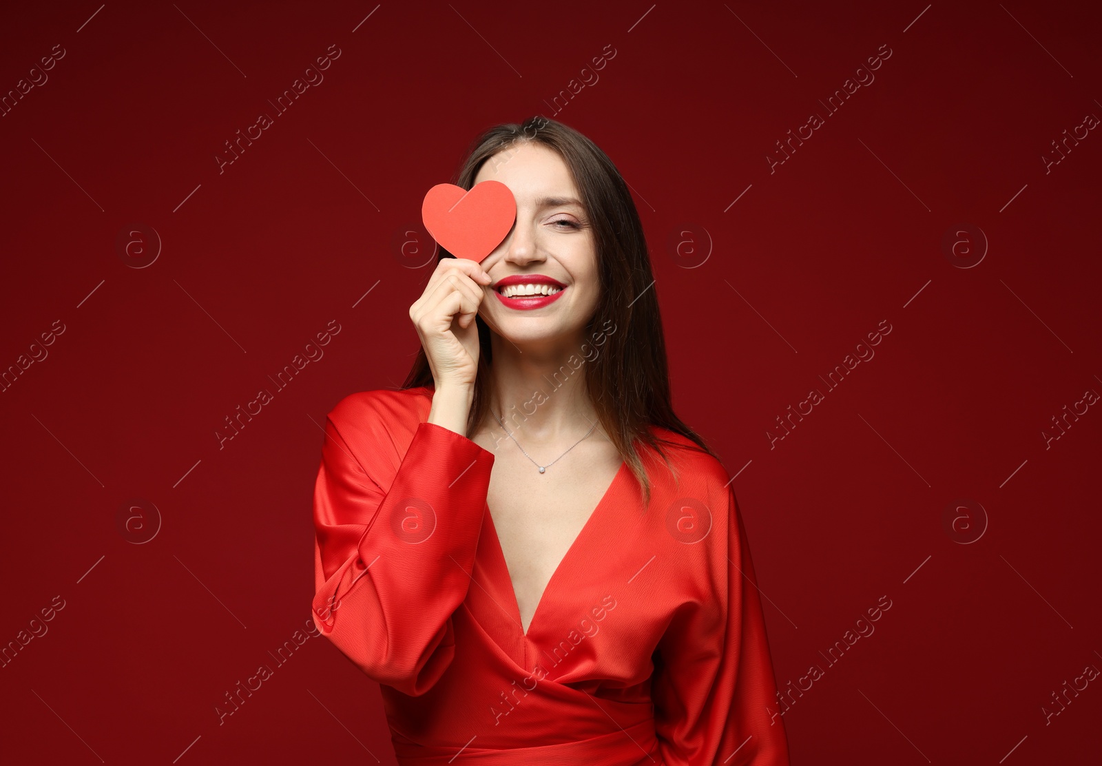 Photo of Happy Valentine's Day. Beautiful woman with paper heart on red background