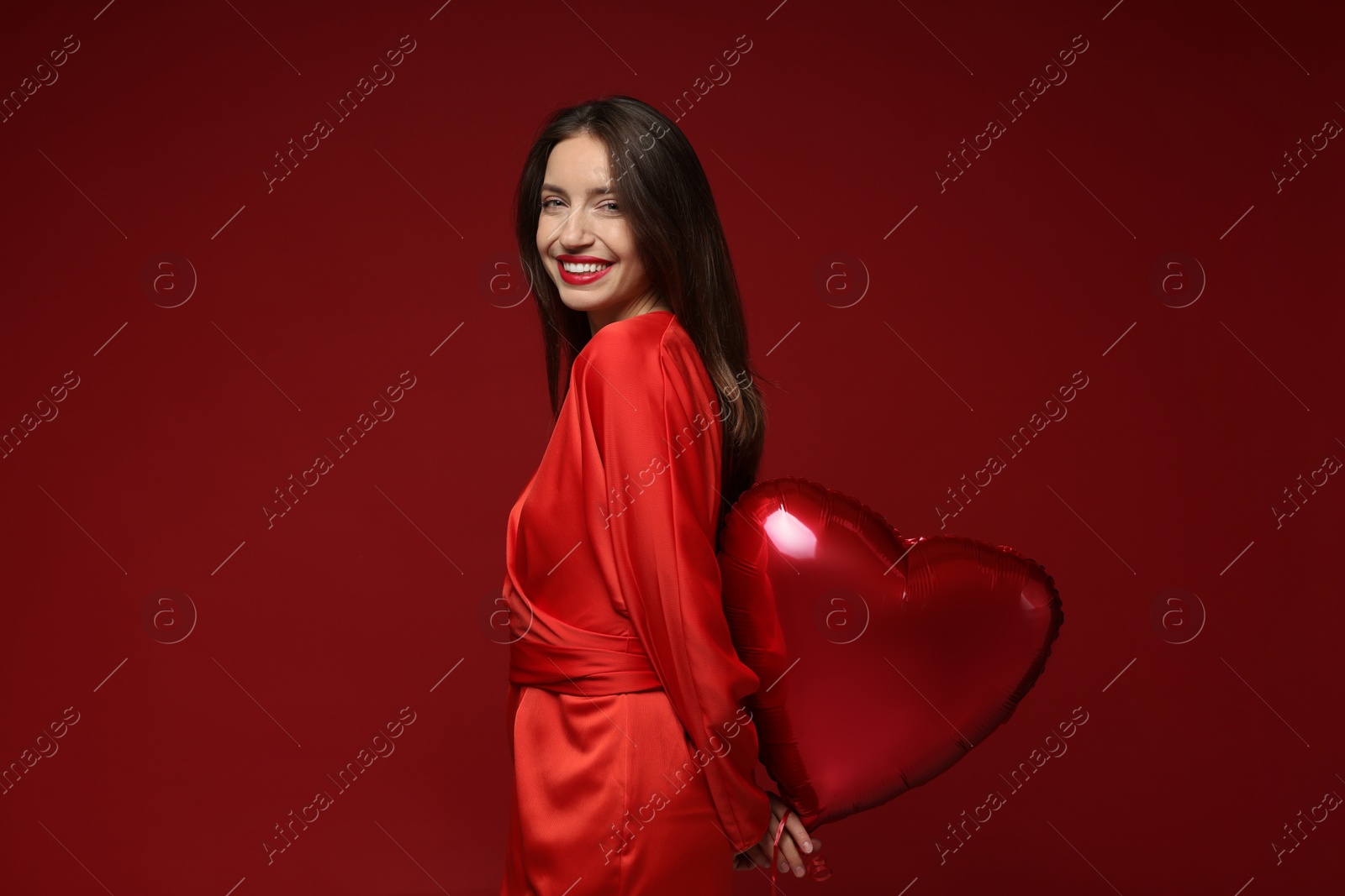 Photo of Happy Valentine's Day. Beautiful woman with heart shaped balloon on red background