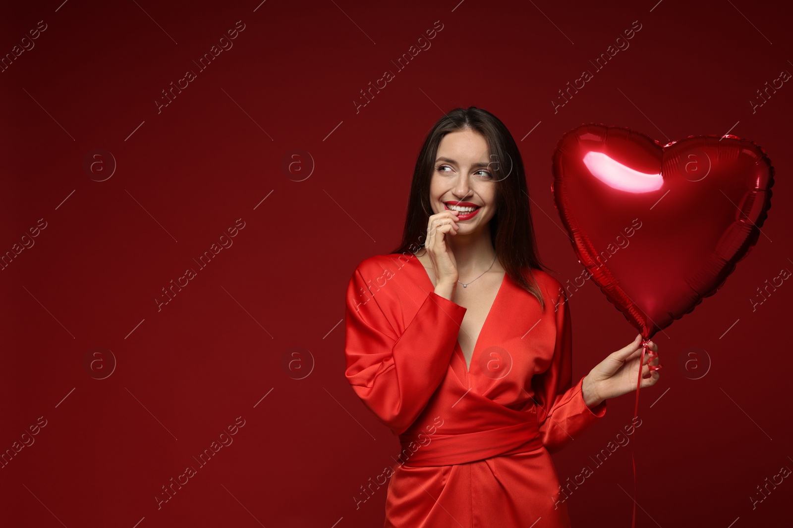 Photo of Happy Valentine's Day. Beautiful woman with heart shaped balloon on red background. Space for text