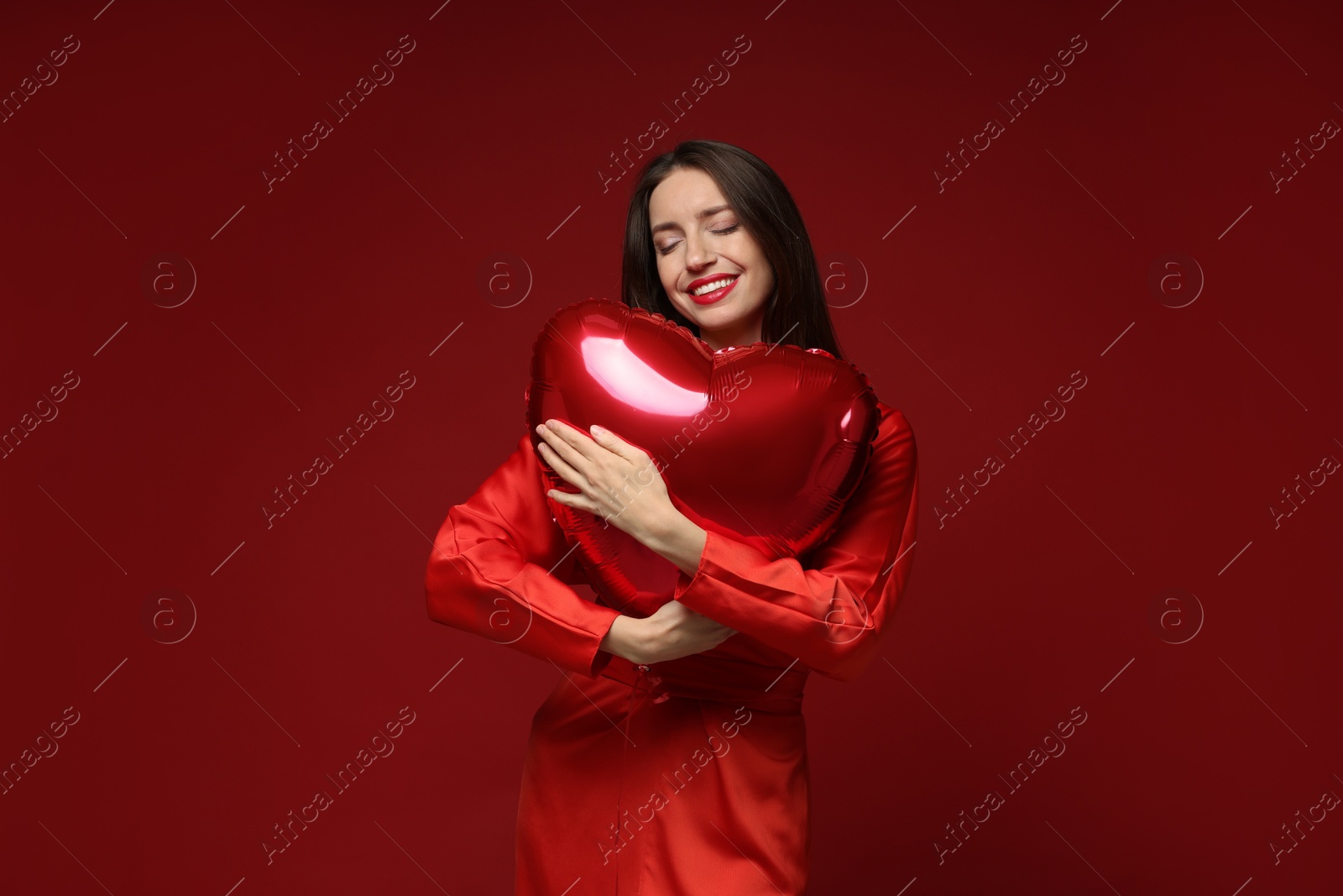 Photo of Happy Valentine's Day. Beautiful woman with heart shaped balloon on red background