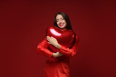 Photo of Happy Valentine's Day. Beautiful woman with heart shaped balloon on red background