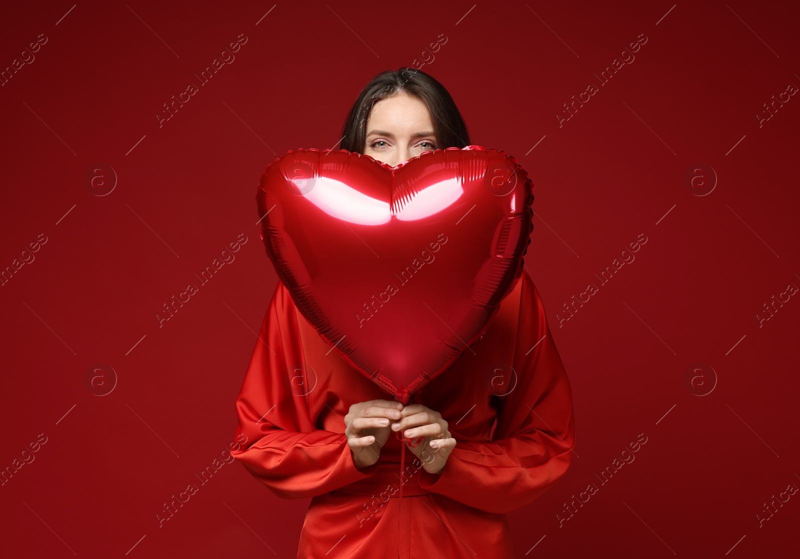 Photo of Happy Valentine's Day. Beautiful woman with heart shaped balloon on red background