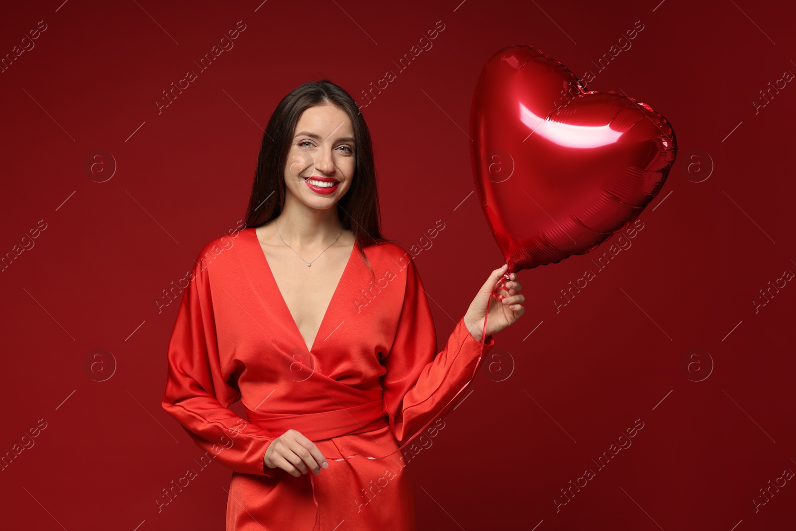 Photo of Happy Valentine's Day. Beautiful woman with heart shaped balloon on red background