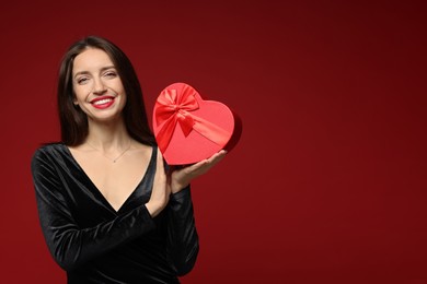 Photo of Happy Valentine's Day. Beautiful woman with heart shaped gift box on red background. Space for text