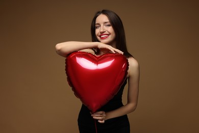 Photo of Happy Valentine's Day. Beautiful woman with heart shaped balloon on brown background