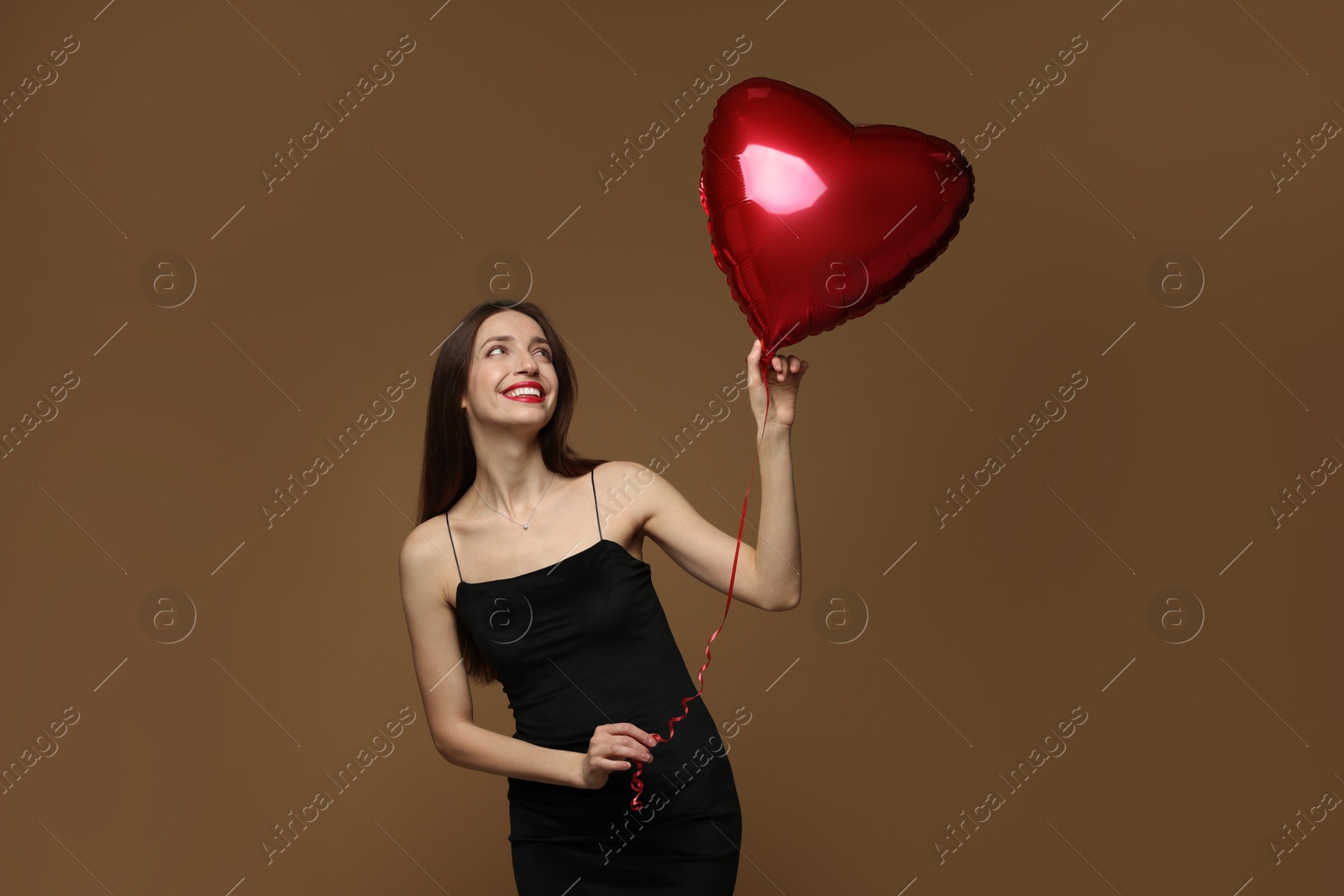 Photo of Happy Valentine's Day. Beautiful woman with heart shaped balloon on brown background