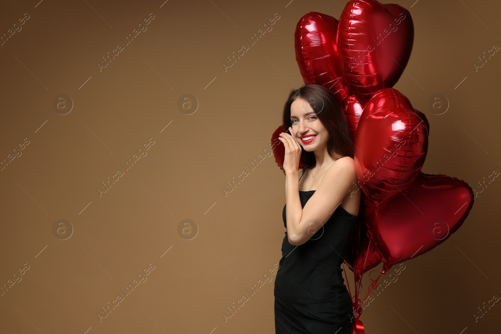 Photo of Happy Valentine's Day. Beautiful woman with heart shaped balloons on brown background. Space for text