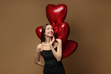 Photo of Happy Valentine's Day. Beautiful woman with heart shaped balloons on brown background