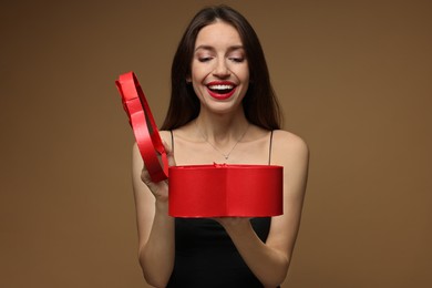 Photo of Happy Valentine's Day. Beautiful woman opening gift on brown background