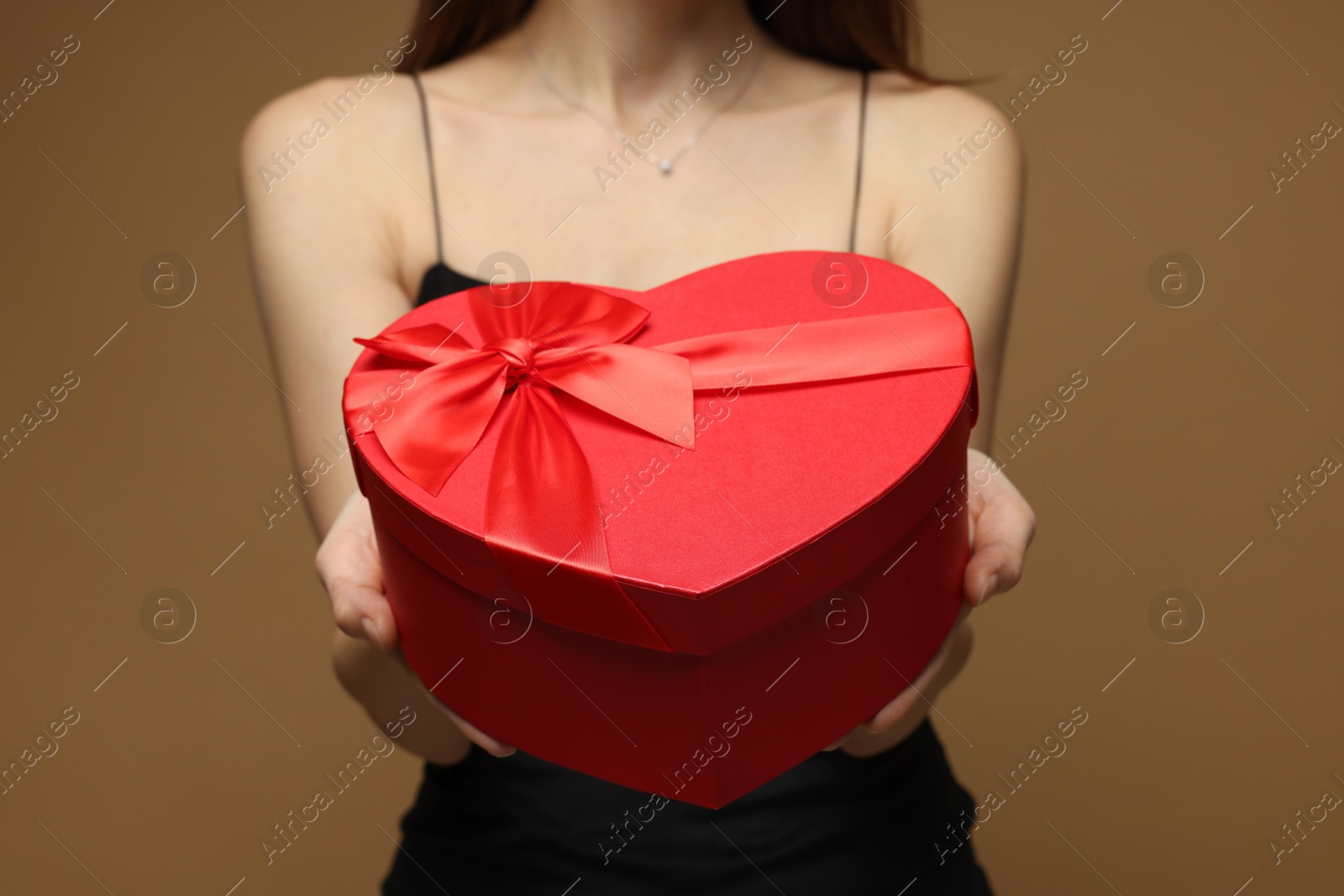 Photo of Happy Valentine's Day. Woman with heart shaped gift box on brown background, closeup