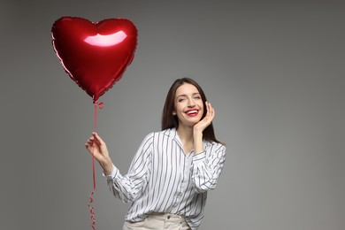 Photo of Happy Valentine's Day. Beautiful woman with heart shaped balloon on grey background