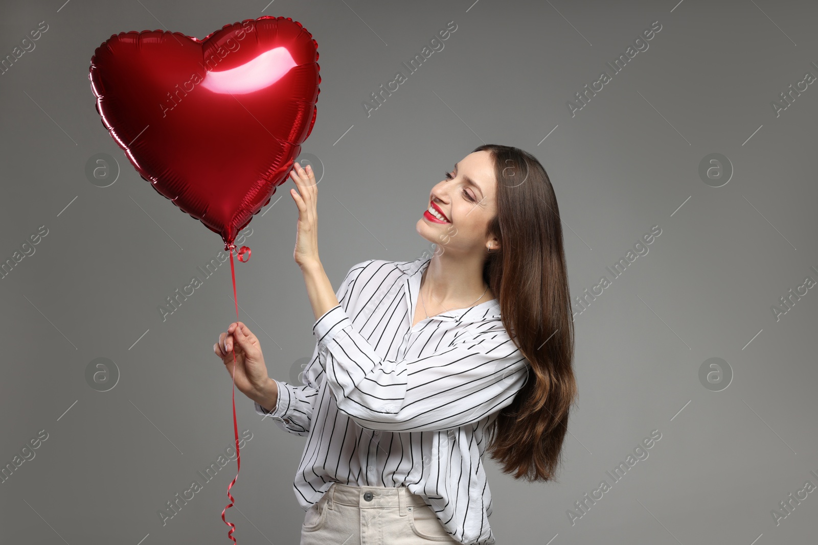 Photo of Happy Valentine's Day. Beautiful woman with heart shaped balloon on grey background