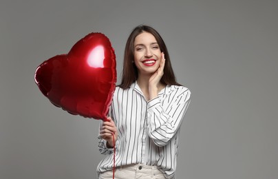 Photo of Happy Valentine's Day. Beautiful woman with heart shaped balloon on grey background