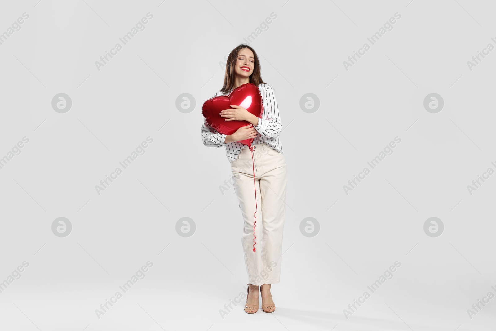 Photo of Happy Valentine's Day. Beautiful woman with heart shaped balloon on white background