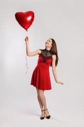 Photo of Happy Valentine's Day. Beautiful woman with heart shaped balloon on white background