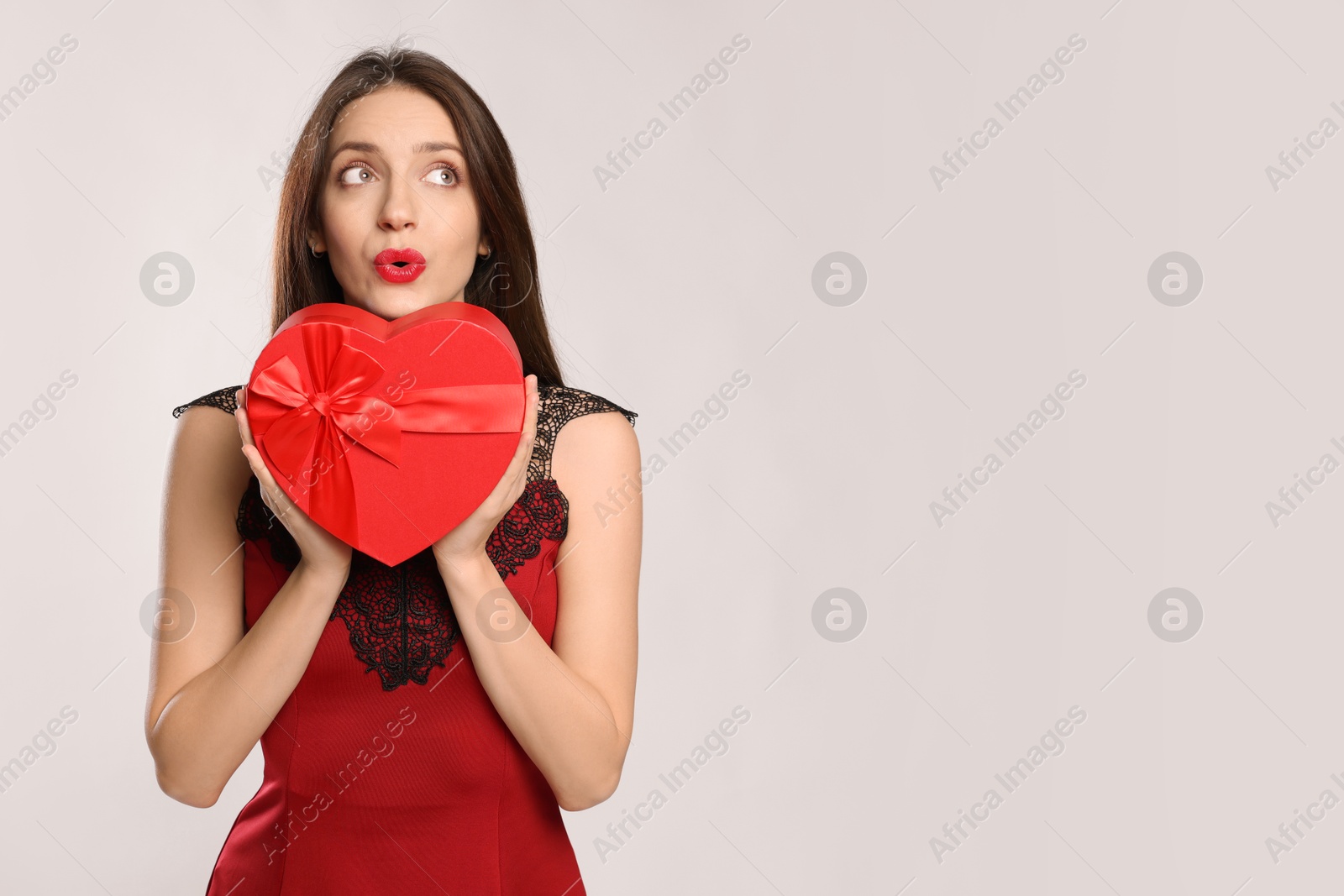 Photo of Happy Valentine's Day. Beautiful woman with heart shaped gift box sending air kiss on white background. Space for text