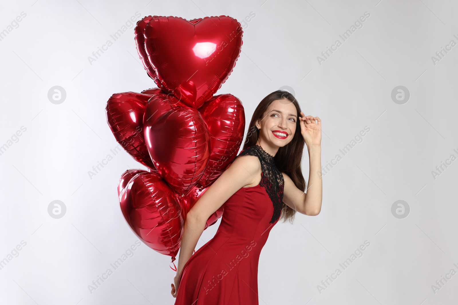 Photo of Happy Valentine's Day. Beautiful woman with heart shaped balloons on white background