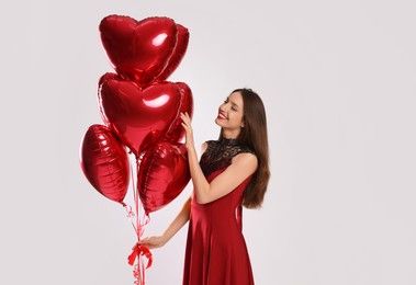 Photo of Happy Valentine's Day. Beautiful woman with heart shaped balloons on white background